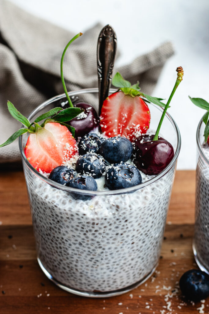 The chia pudding in to glasses topped with fresh berries and shredded coconut.