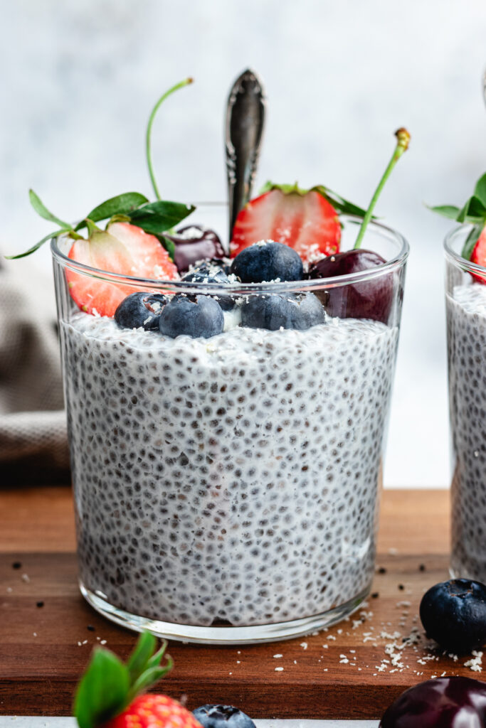 The chia pudding in to glasses topped with fresh berries and shredded coconut.