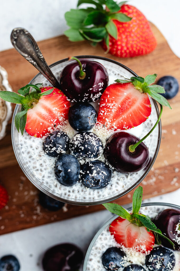 The chia pudding in to glasses topped with fresh berries and shredded coconut.