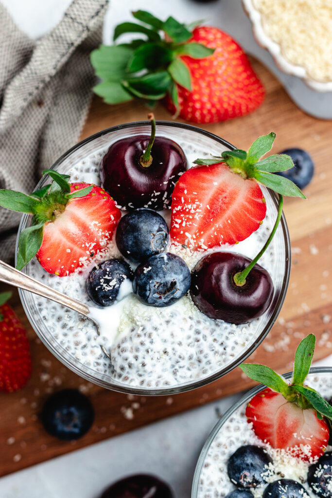 The chia pudding in to glasses topped with fresh berries and shredded coconut.