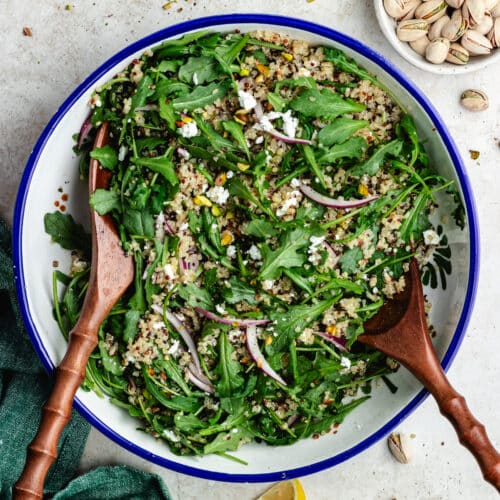 The salad in a salad bowl with lemon and pistachios on the side.