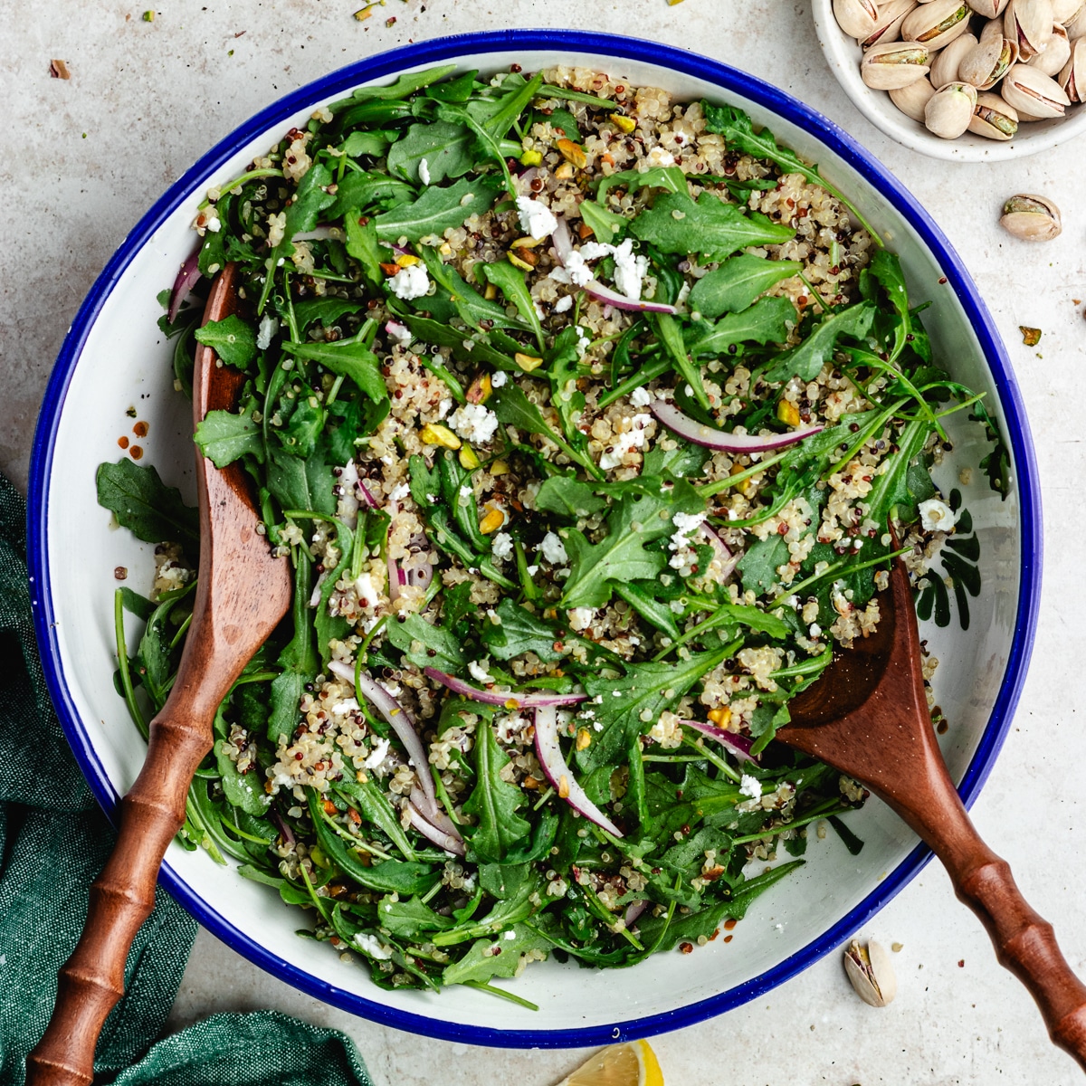 The salad in a salad bowl with lemon and pistachios on the side.
