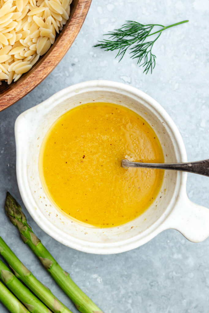 The dressing in a small bowl with a spoon.