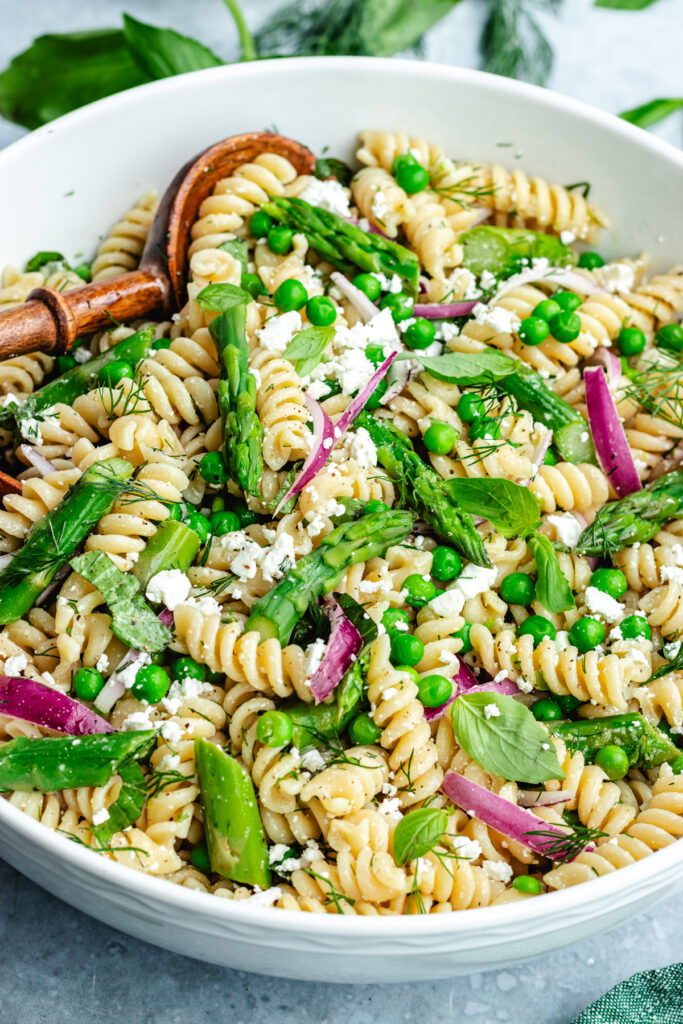 The salad in a bowl topped with feta cheese and fresh herbs.