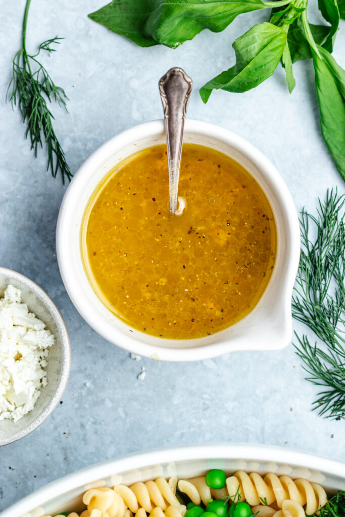 The dressing in a small bowl with a spoon.