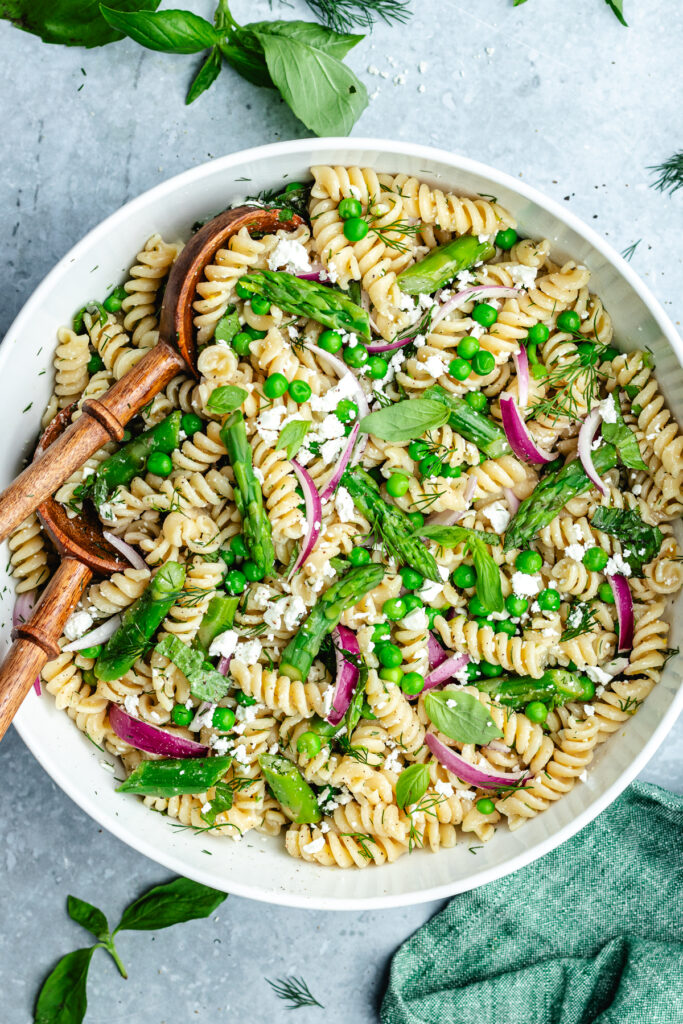 The salad in a bowl topped with feta cheese and fresh herbs.