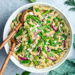 The salad in a bowl topped with feta cheese and fresh herbs.