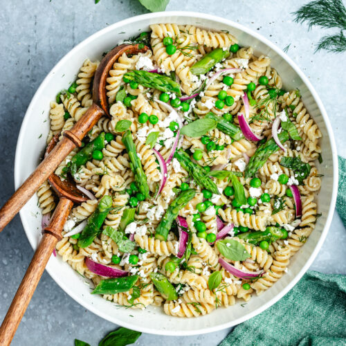 The salad in a bowl topped with feta cheese and fresh herbs.