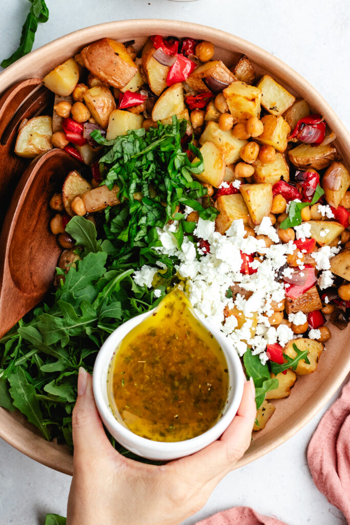 Pouring over the dressing over the salad.