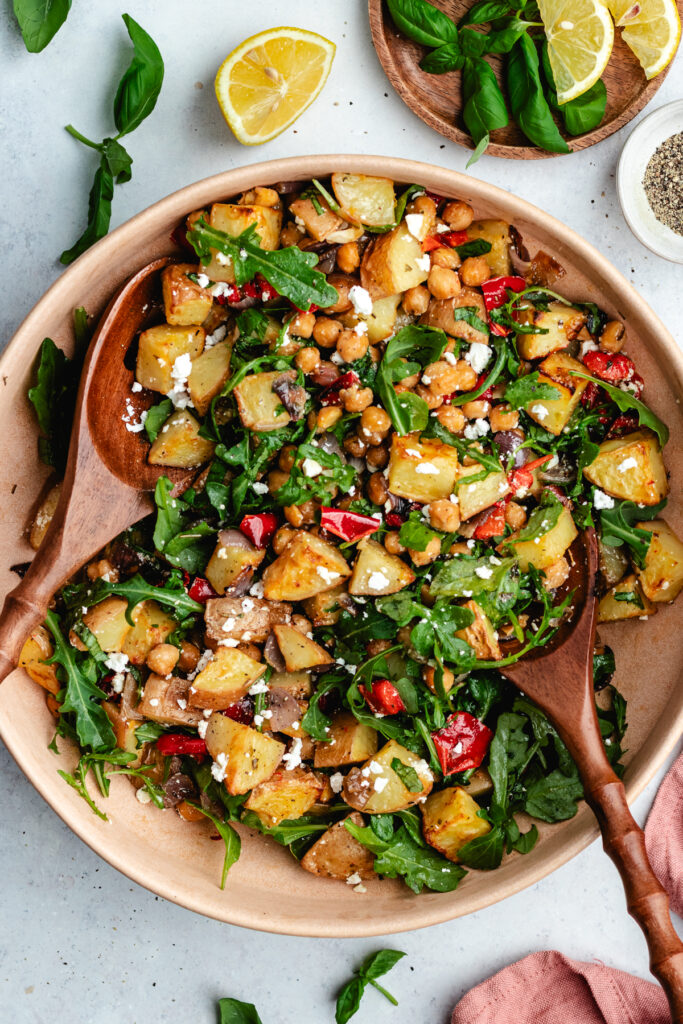 The potato salad in a bowl topped with feta cheese and fresh basil.
