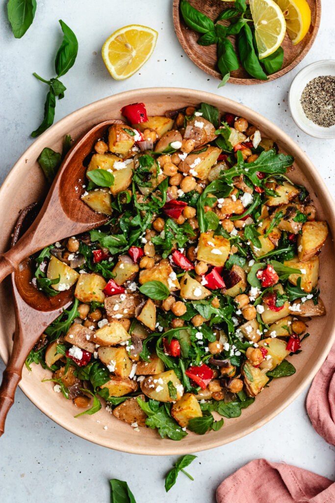 The potato salad in a bowl topped with feta cheese and fresh basil.