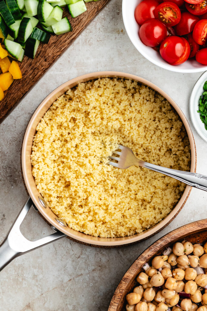 The cooked couscous in a saucepan with a fork.