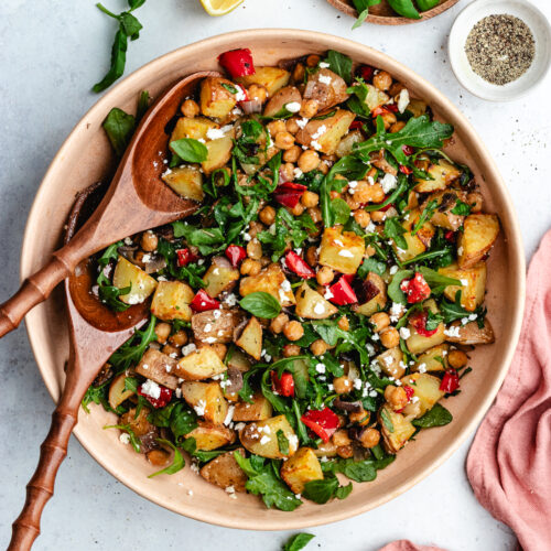 The potato salad in a bowl topped with feta cheese and fresh basil.
