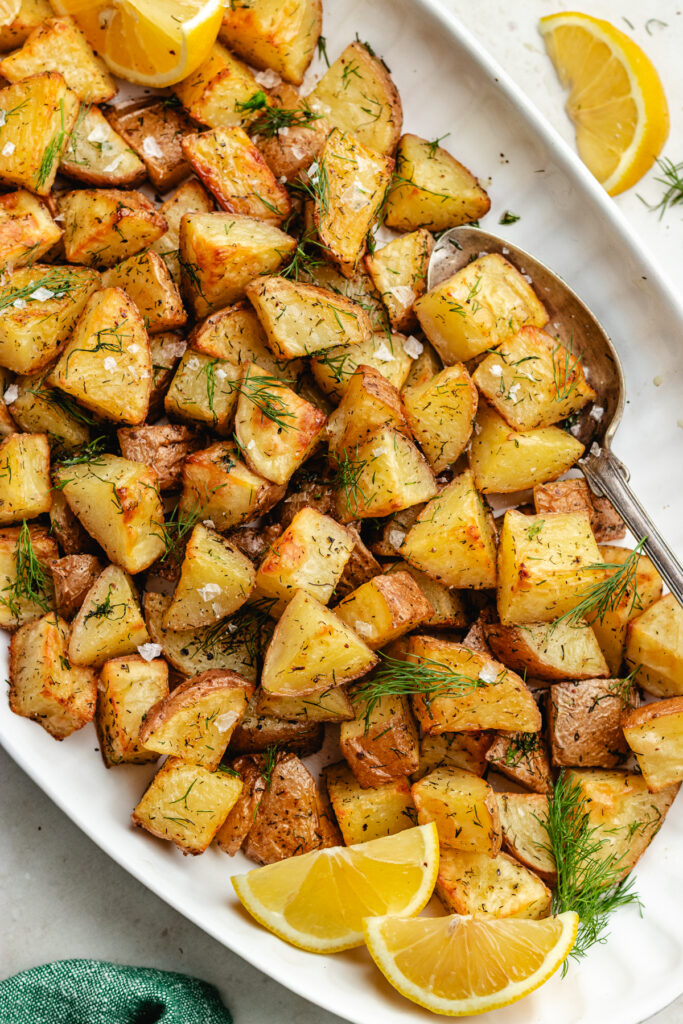 The roasted dill potatoes on a serving platter topped with fresh dill.