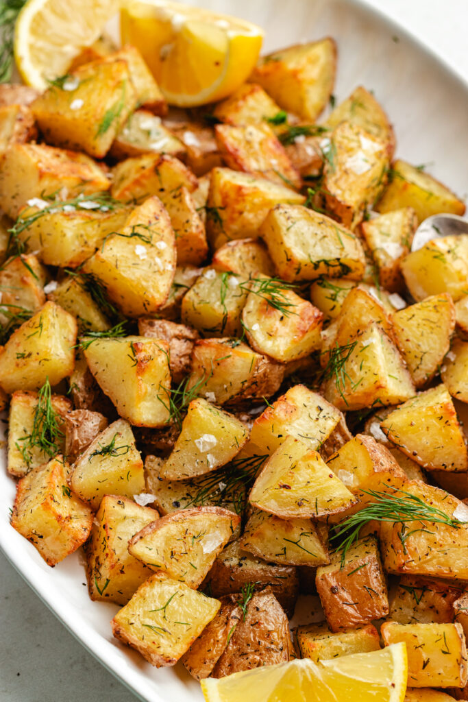 The roasted dill potatoes on a serving platter topped with fresh dill.