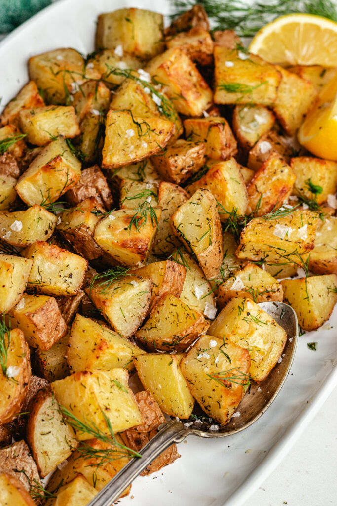 The roasted dill potatoes on a serving platter topped with fresh dill.