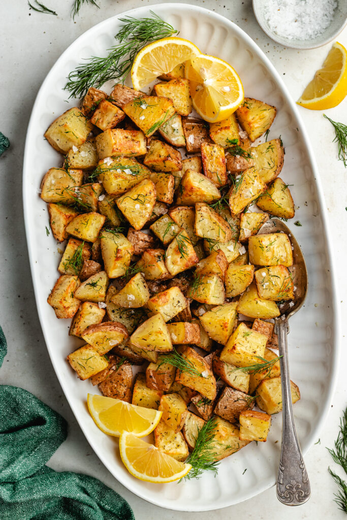 The roasted dill potatoes on a serving platter topped with fresh dill.