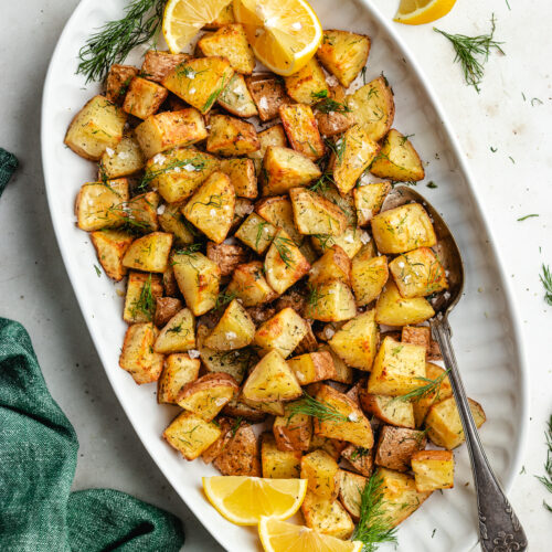 The roasted dill potatoes on a serving platter topped with fresh dill.
