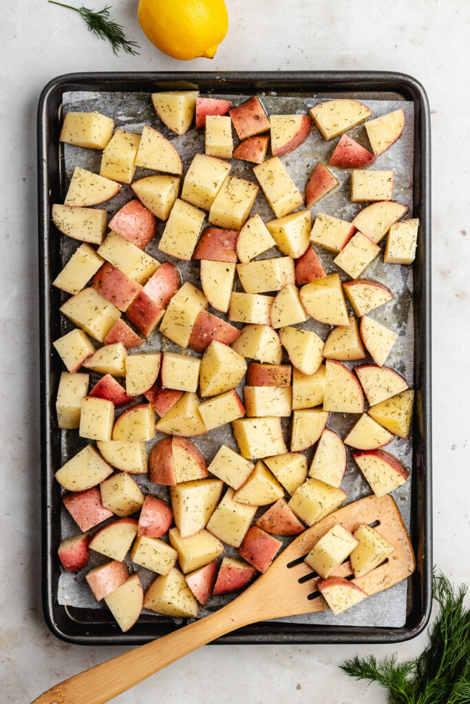 The potatoes with the spices, oil and butter on a baking sheet.