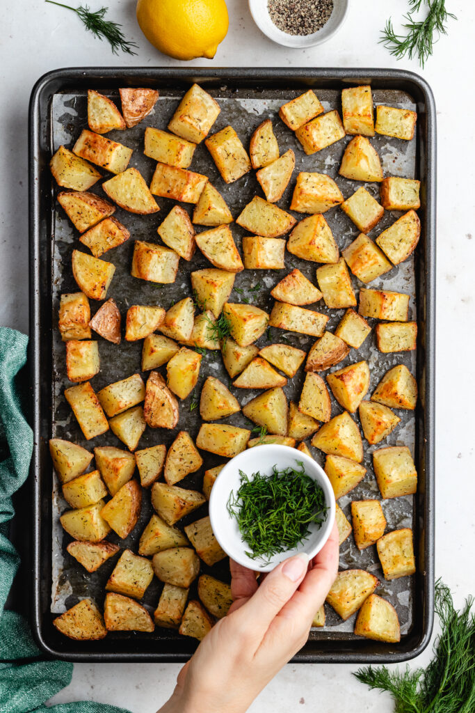 Adding fresh chopped dill to the roasted potatoes.