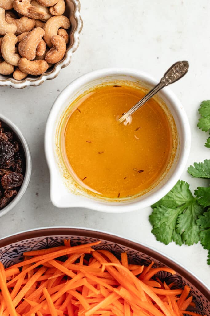 The dressing in a small bowl with a spoon.