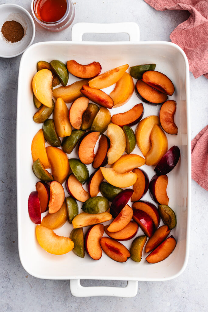 The quartered plums in a baking dish.