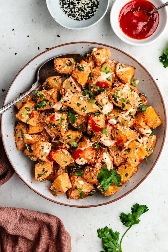 The potato salad on a bowl topped with sauce and fresh herbs.
