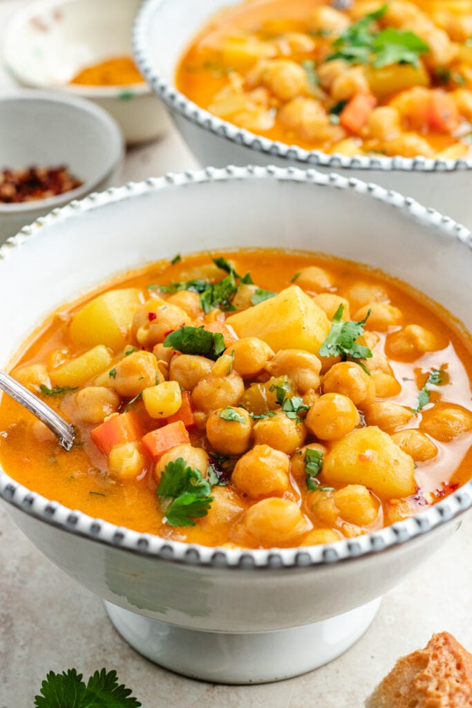 The soup in two bowls topped with fresh herbs.
