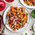 The farro salad on two plates topped with herbs and pomegranate.