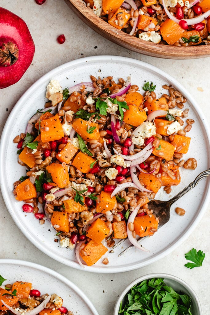 The farro salad on two plates and in a salad bowl.