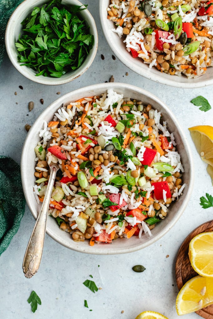 The rice salad in two bowls topped with fresh herbs.