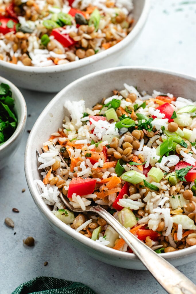 The rice salad in two bowls topped with fresh herbs.