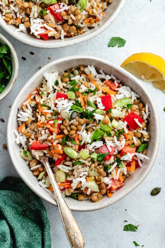 The rice salad in two bowls topped with fresh herbs.